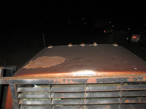 1977 Ford F-250 - A rusty truck roof is seen at night with other vehicles in the background.
