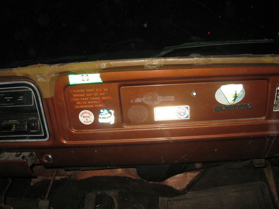 Dashboard of a 1977 Ford F-250 with a 'Custom' badge and warning stickers
