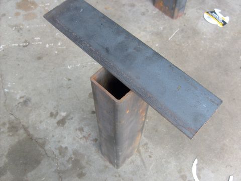 1986 Ford Bronco - Two metal components are shown resting on a concrete surface, possibly in a workshop or garage.