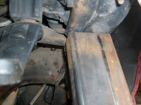 1986 Ford Bronco - Close-up view of the rusty undercarriage of a vehicle, showing frame and suspension parts.