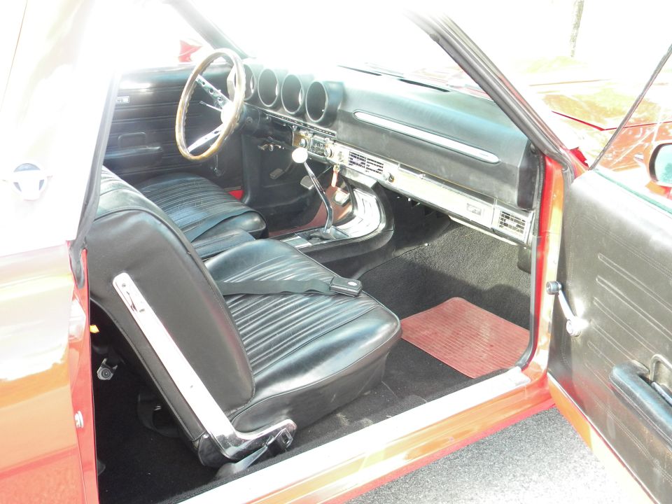 Interior view of a red car with black seats and a wooden steering wheel