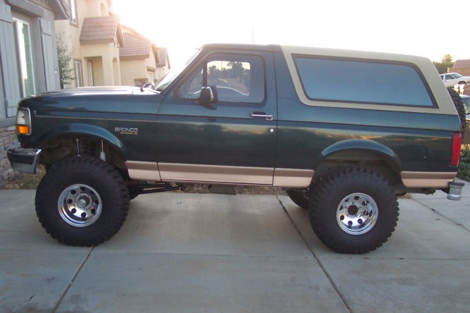 Green Ford Bronco with tan top, lifted with big tires