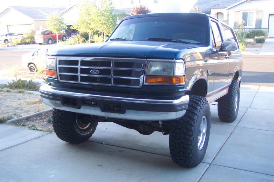 Dark blue Ford Bronco with lifted suspension and large tires, front 3/4 view