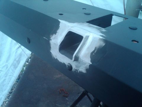 1987 Suzuki Samurai - A close-up view of a black bumper part that has been prepared with body filler around a square cutout.