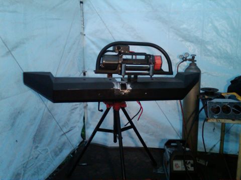 1987 Suzuki Samurai - A custom bumper assembly, complete with a winch, is displayed on a tripod in a workshop setting.