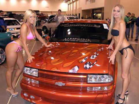 1991 Ford Crown Victoria - Customized orange pickup truck with flame and checkered flag graphics displayed indoors.