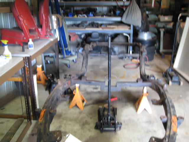 Car frame assembly supported by jack stands in a garage workshop