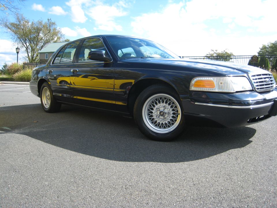 Black Ford Crown Victoria with aftermarket wheels parked on asphalt
