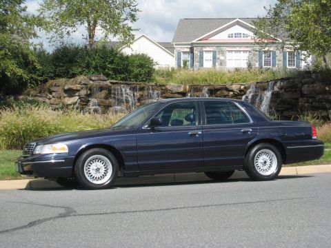 1999 Ford Crown Victoria - This 1999 Ford Crown Victoria is seen from the side, parked in front of a house with a waterfall feature.