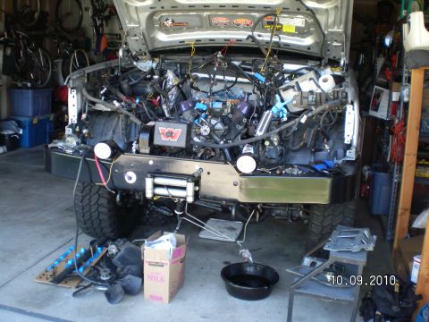 1996 Ford Bronco - Front end of a truck torn down in a garage with the grille, radiator and fenders removed, exposing the V8 engine, wiring harness and a Warn…