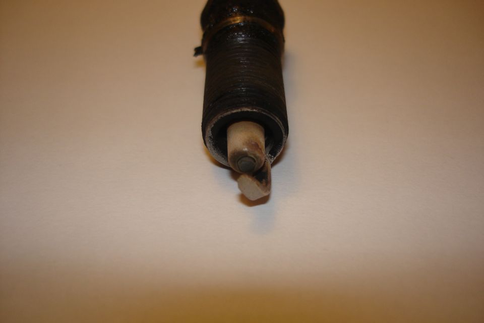 Used spark plug with carbon-fouled threads and scorched ceramic insulator
