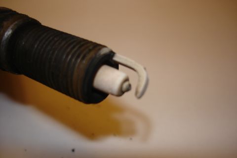 2003 Chrysler Town & Country - A close-up view of a used spark plug, showing wear on the electrode and insulator.