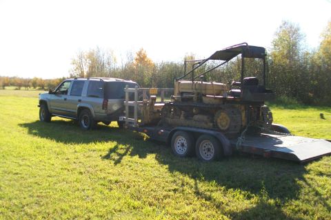 2000 Chevrolet Tahoe - A Chevrolet Tahoe tows a bulldozer on a flatbed trailer through a grassy area.