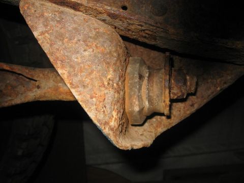 1981 Ford Bronco - Close-up view of heavily rusted undercarriage components, including a bracket and bolt.