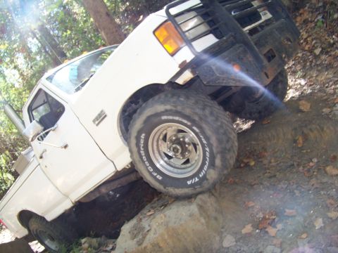 1987 Ford F-250 - A white Ford F-250 navigates a rocky trail, with another vehicle visible in the background.