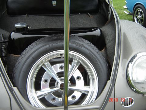 1993 Ford Bronco - Spare tire and fuel tank in a car's trunk, with a blue car visible outside.