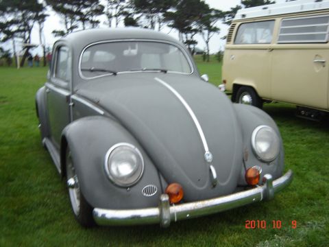 1993 Ford Bronco - A classic Volkswagen Beetle is parked on a grassy field next to a vintage van.