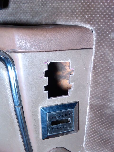 1986 Ford Bronco - Close-up of an interior panel showing a cut-out and an unlock/lock switch, likely for a power window or lock mechanism.