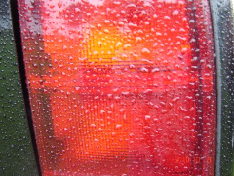 1993 Ford Bronco - Water droplets cling to the red and orange lens of a vehicle's tail light.