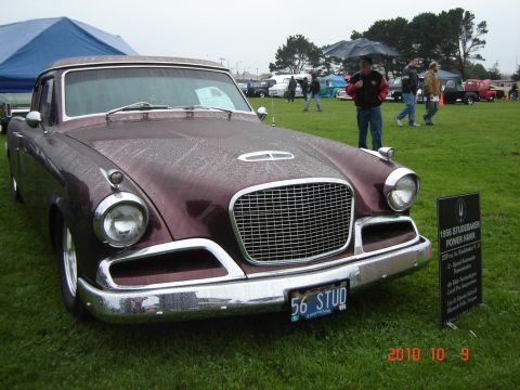1993 Ford Bronco - A maroon 1956 Studebaker Power Hawk is displayed on a grassy field, with a sign providing details about the vehicle.