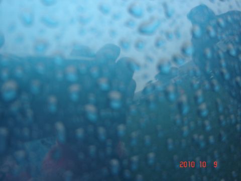 1993 Ford Bronco - Water droplets obscure the view of a blue vehicle's exterior.