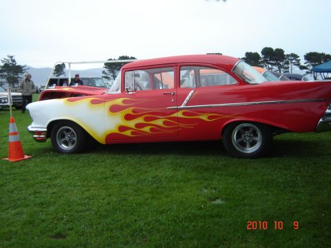 1993 Ford Bronco - A classic 1955 Chevrolet sedan with custom flame paintwork is displayed on a grassy field.