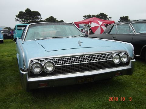 1993 Ford Bronco - Light blue Lincoln Continental parked on grass at an outdoor event, with other vehicles and tents in the background.