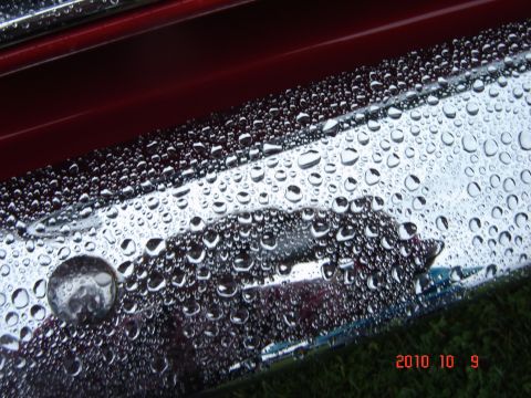 1993 Ford Bronco - Water droplets cover the chrome trim of a red vehicle.