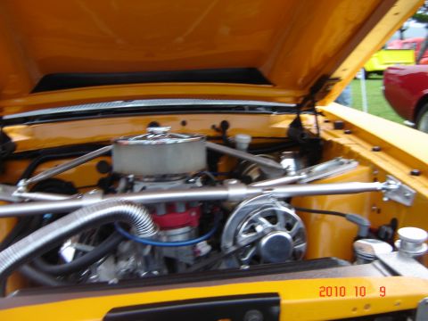 1993 Ford Bronco - Engine bay details of a yellow vehicle with a red car in the background.