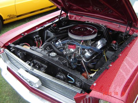 1993 Ford Bronco - The engine bay of a red car is shown, with a yellow car visible in the background.