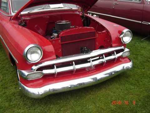 1993 Ford Bronco - 1953 Chevrolet Bel Air front end with hood open, parked on grass next to another car.