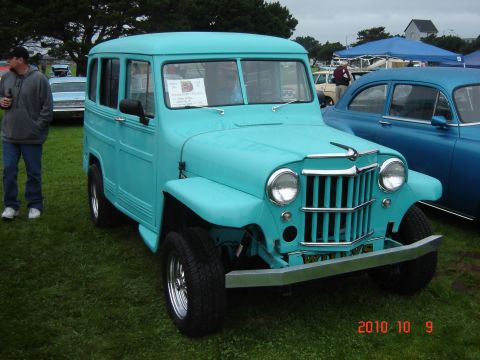 1993 Ford Bronco - A turquoise Jeep station wagon is parked on grass at an outdoor event with other vehicles present.
