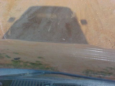1989 Ford Bronco - The shadow of a vehicle is cast on a dusty surface, viewed from inside.