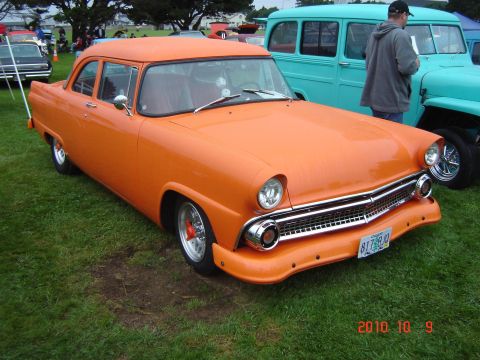 1993 Ford Bronco - This orange sedan, likely a 1955 model, is parked on grass with other vehicles in the background.
