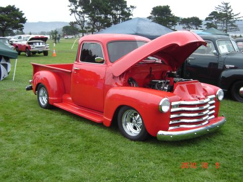 1993 Ford Bronco - Customized red pickup truck on display at an outdoor event with other vehicles present.