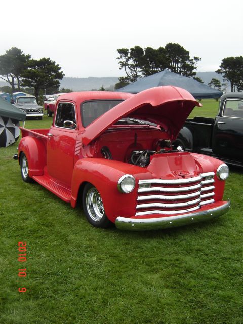 1993 Ford Bronco - A classic red pickup truck is displayed with its hood open, its engine bay at an outdoor event.