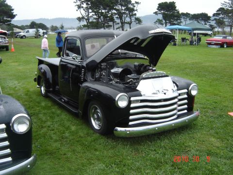 1993 Ford Bronco - A classic black Chevrolet pickup truck is displayed with its hood open at an outdoor event.