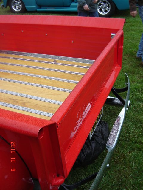 1993 Ford Bronco - Close-up of a red pickup truck bed with wood floor, with another vehicle visible in the background.