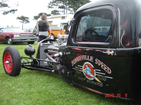 1993 Ford Bronco - A vintage hot rod truck is parked on grass with other vehicles visible in the background.