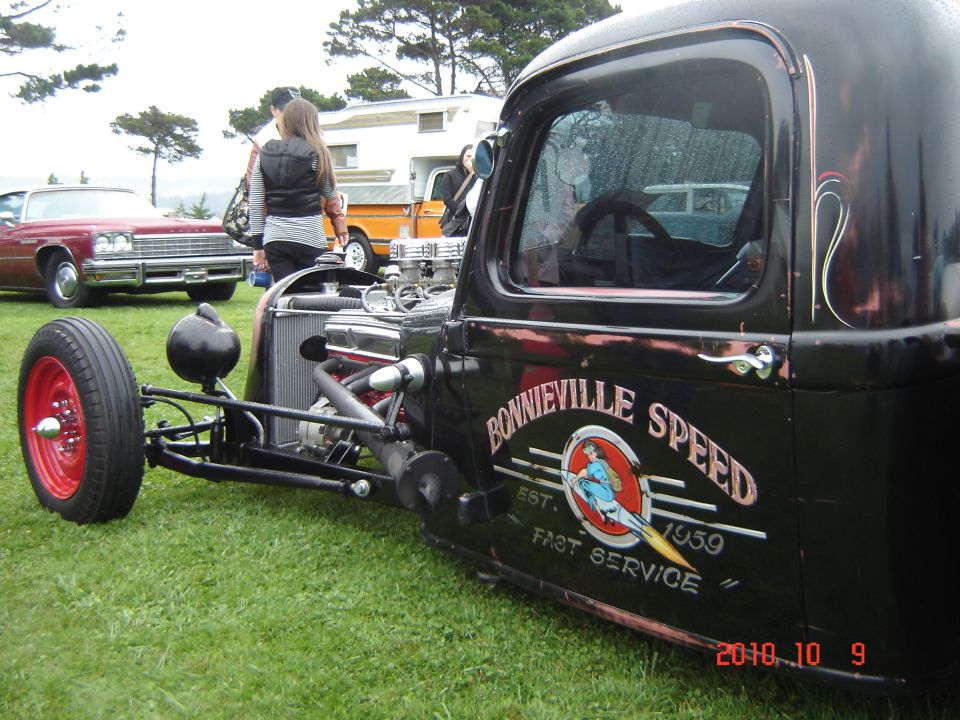 Hot rod truck with 'Bonneville Speed Est. 1959 Fast Service' on the door. Other cars and a camper are in the background