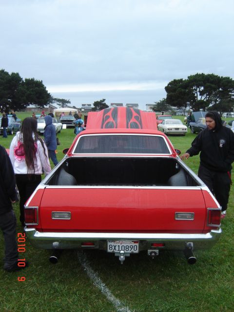 1993 Ford Bronco - A red pickup truck with flame decals on its hood is parked on a grassy field at an outdoor event.