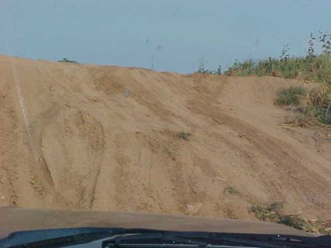1989 Ford Bronco - A dirt hill with tire tracks is seen under a clear blue sky.