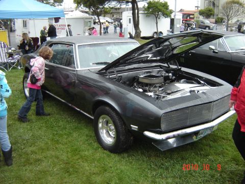 1993 Ford Bronco - A dark gray coupe with its hood open, revealing the engine, sits on display on a grassy field.