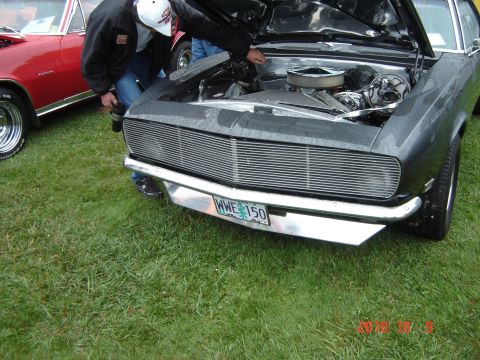 1993 Ford Bronco - A gray car with its hood open is displayed, revealing the engine compartment. Another red car is visible to the left.