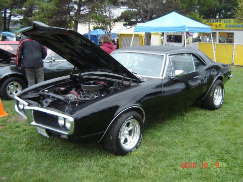 1993 Ford Bronco - Black 1967 Pontiac Firebird on display with hood open, another car visible to the left.