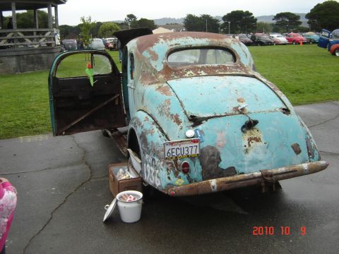 1993 Ford Bronco - This weathered coupe, possibly from 1936, sits with its door ajar, revealing a glimpse of its interior and a bucket nearby.