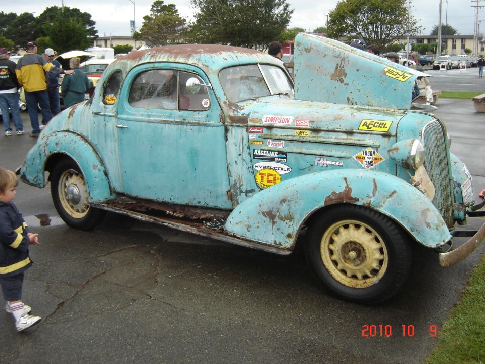 Rusted light blue coupe with racing decals and hood open