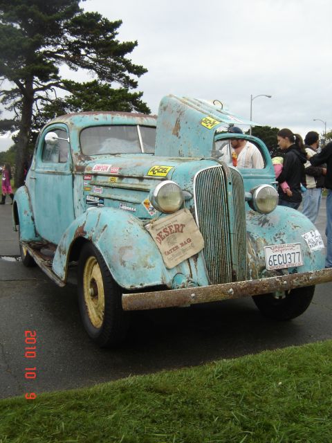 1993 Ford Bronco - This vintage truck, likely from the mid-1930s, displays significant wear and tear, adorned with various stickers and a 'Desert Water Bag'.