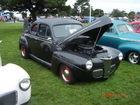 1993 Ford Bronco - A black coupe, possibly a 1941 model, is displayed with its hood open at an outdoor car show.