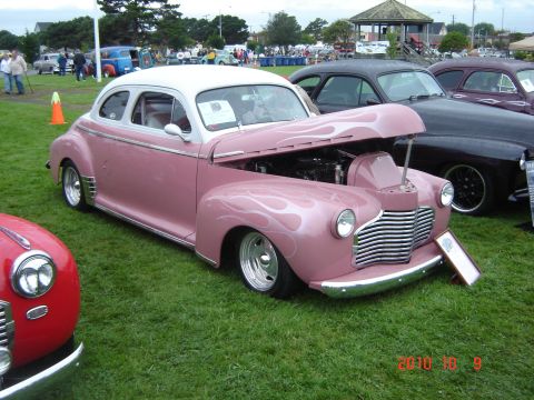1993 Ford Bronco - Customized 1940s coupe with flame paint and open hood at a car show.